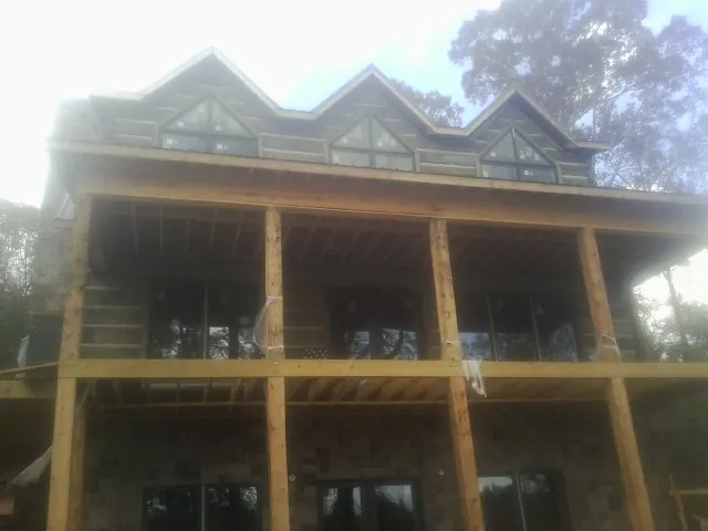 Dormers and porch framing on a large log home under construction — Roof Coating work by our crew in Wakarusa
