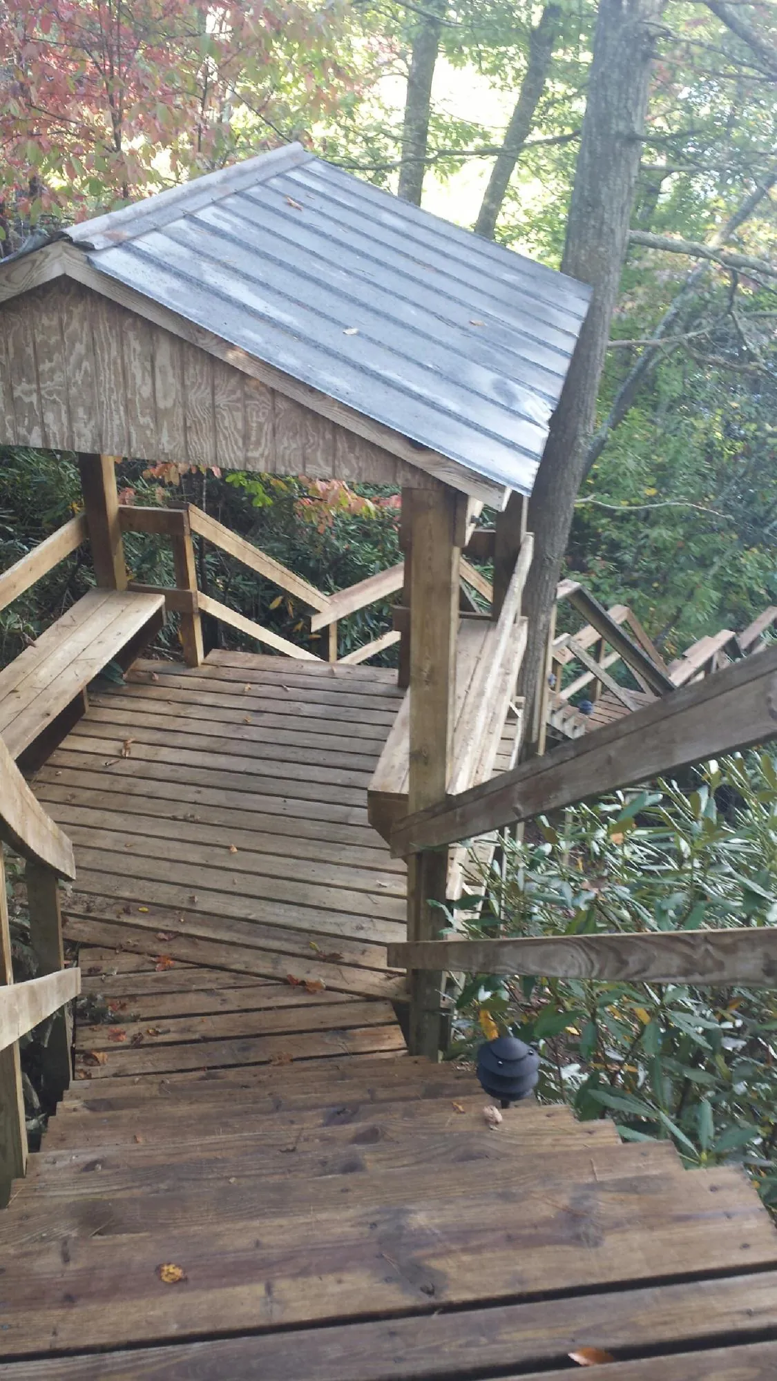Metal roofed shelter over wooden steps on a wooded walkway — Skylight Repair & Installation work by our crew in Wakarusa