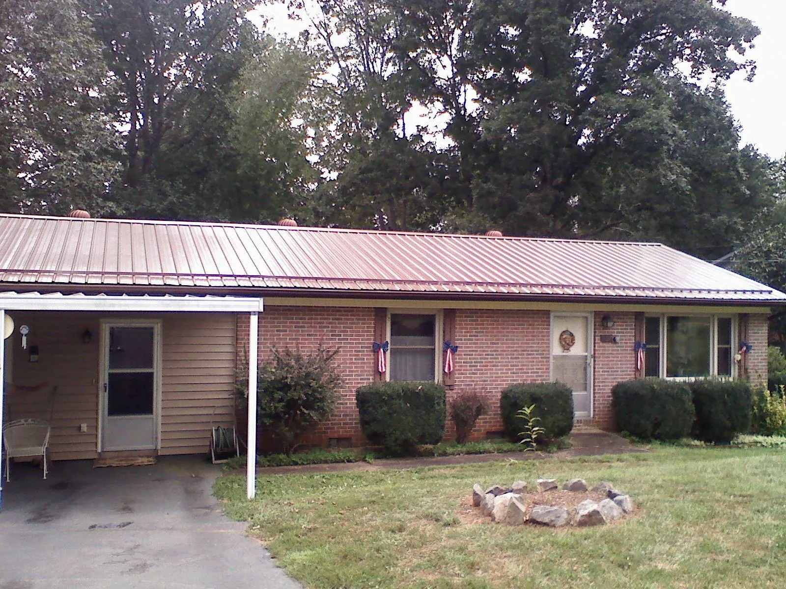 Bronze metal roof and carport on a brick ranch home — Roof Repair work by our crew in Wakarusa