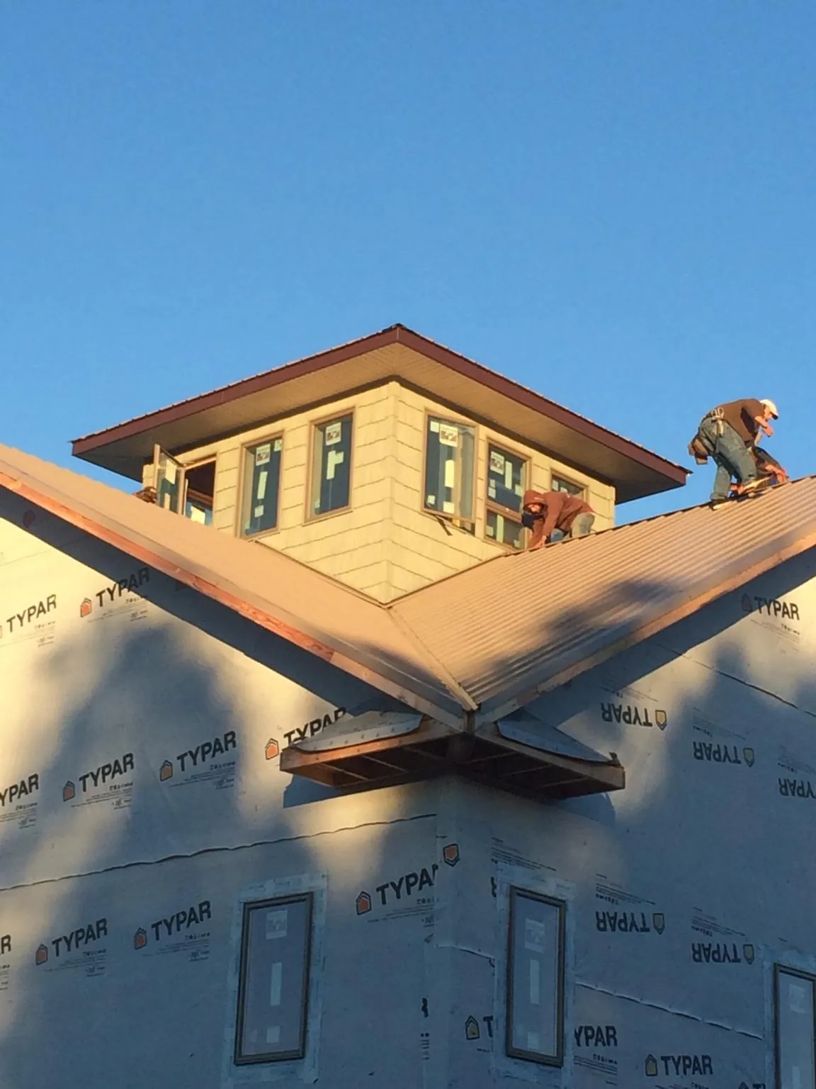 Roofers working around a rooftop cupola on a new metal roof at sunset — Roof Waterproofing in Wakarusa by Roofing Brothers